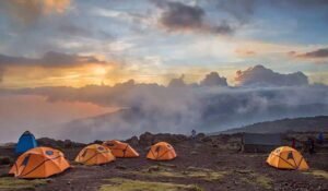 Colorful mountain tents set up at Kilimanjaro base camp with porters preparing equipment in the foreground